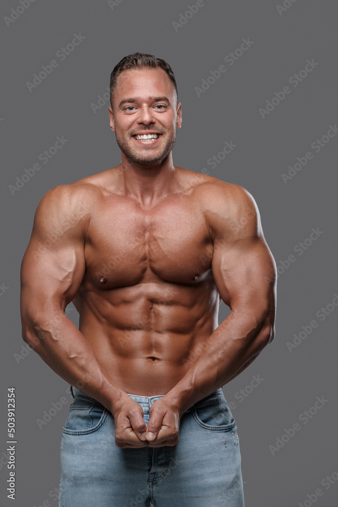 Portrait of happy muscular man with naked torso against gray background. Portrait of happy muscular man with naked torso against gray background.