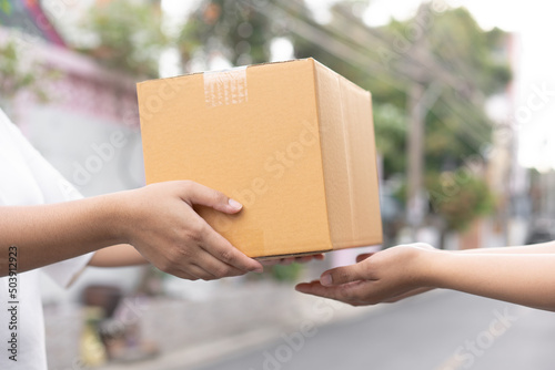 Postal service sending paper cardboard box to customer in front of a house outdoor. Shipping service arrival and send to customer address.