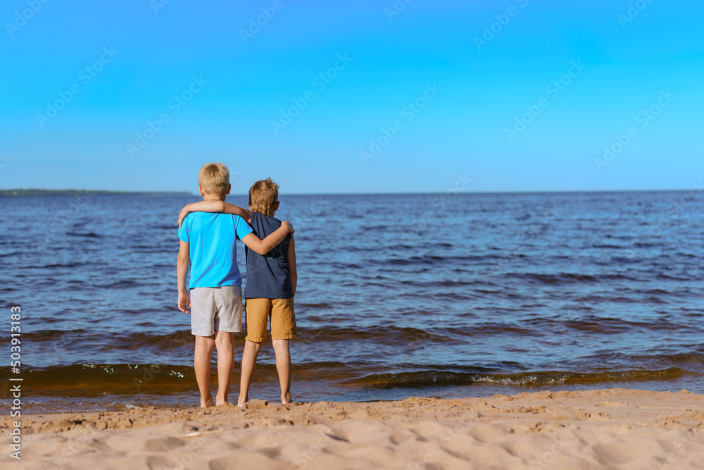 boys standing on beach lookind at horizon over Ladoga lake, Russia boys standing on beach lookind at horizon over Ladoga lake, Russia