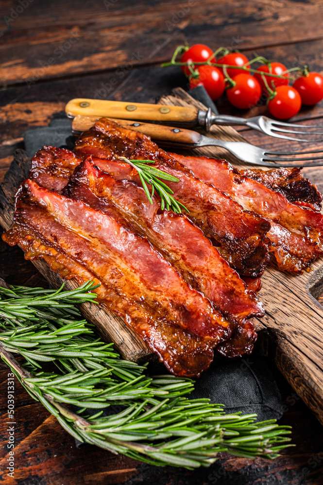 Roasted pork Bacon sizzling slices on wooden board. Wooden background. Top view