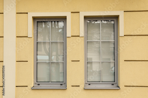 Yellow wall of building with stylish grey windows