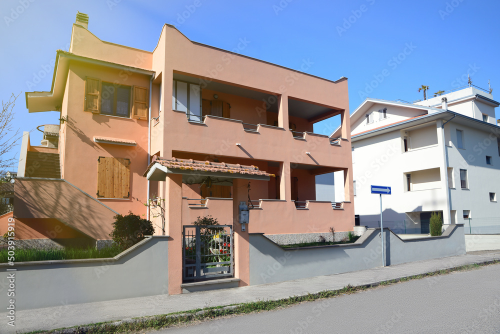 Modern apartment building with fence on sunny day