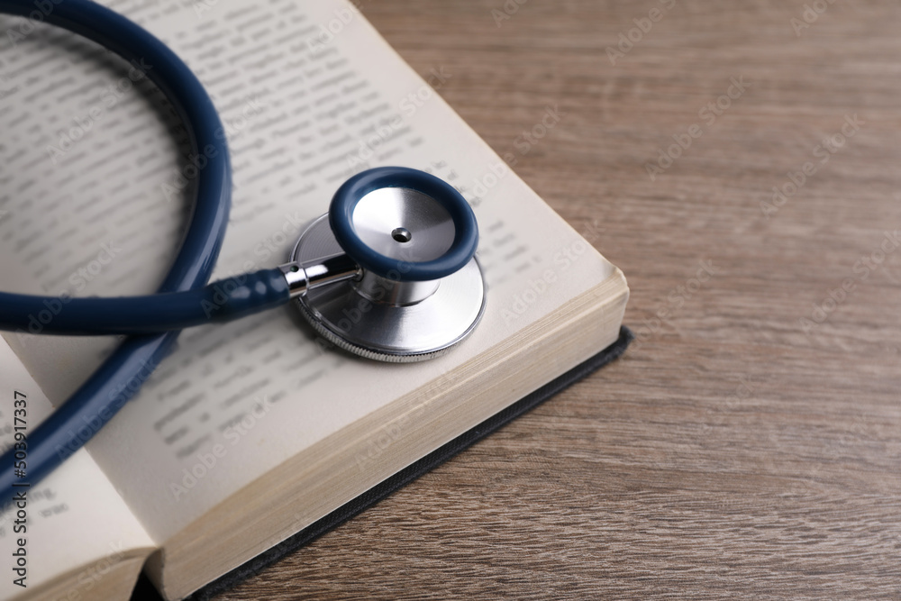 Student textbook and stethoscope on wooden table, closeup. Medical education Student textbook and stethoscope on wooden table, closeup. Medical education