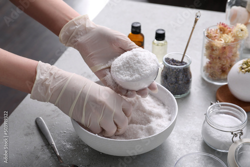 Woman in gloves making bath bomb at grey table, closeup photo