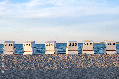 Six beach chairs on the sandy beach at the baltic sea.