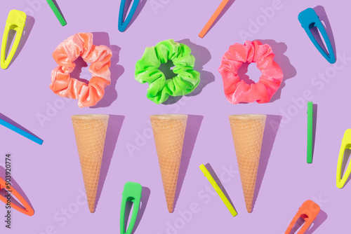 Summer creative layout with colorful scrunchies, hair pins and ice cream cone on pastel purple background. 80s or 90s retro fashion aesthetic ice cream concept. Minimal hair  assesories idea. photo