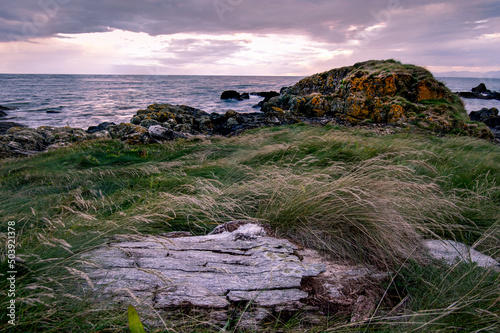 Rocky seascape beside Turnberry point lighthouse with cloudy moody sky  at coast line photo