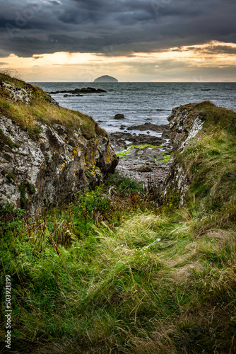 Rocky seascape beside Turnberry point lighthouse with cloudy moody sky  at coast line with view of ailsa craig Fototapet