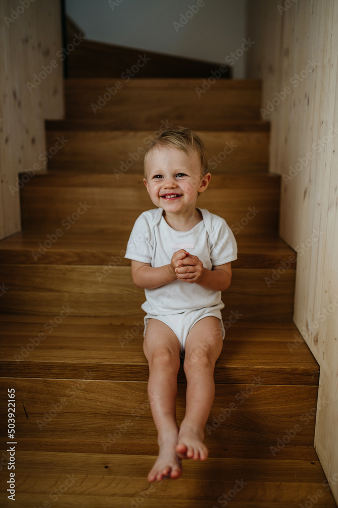 Cute little girl sitting on stairs at home and looking at camera. Cute little girl sitting on stairs at home and looking at camera.