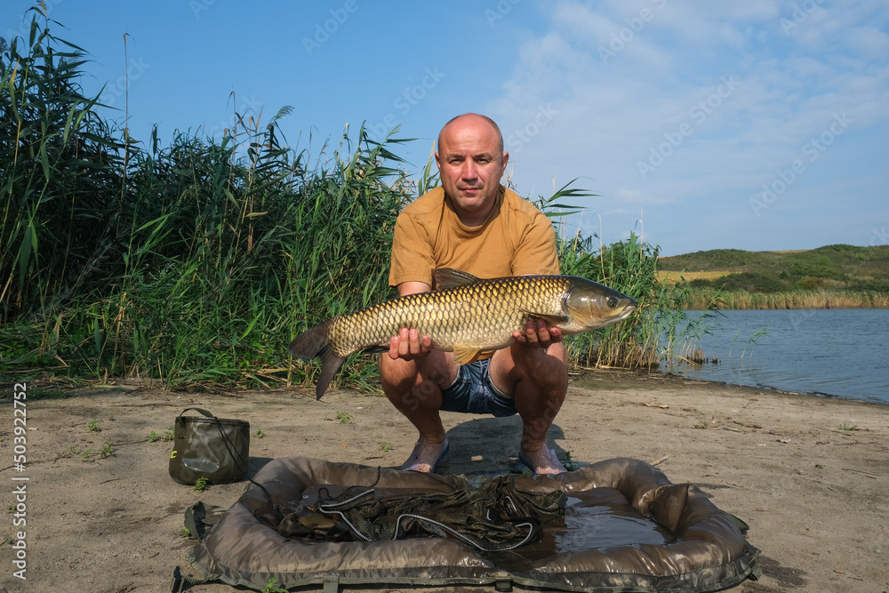 Happy angler with big fish trophy in hands. Success carp fishing. Happy angler with big fish trophy in hands. Success carp fishing.