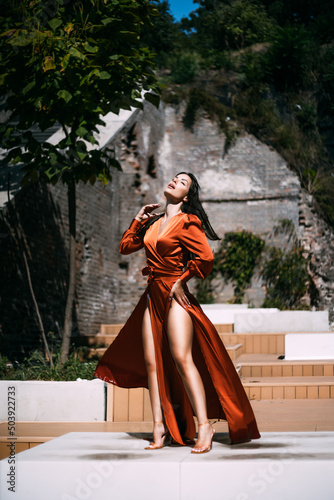 Sensual brunette beautiful woman luxury model posing in fluttering long dress outdoor