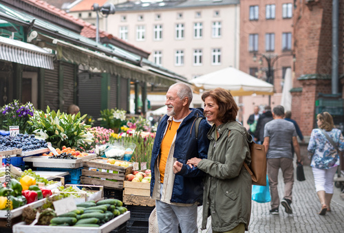 Happy senior couple tourists buying fruit outdoors on market in town. © Halfpoint