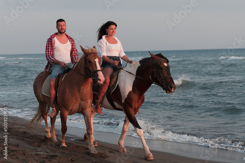a loving young couple in summer clothes riding a horse on a sandy beach at sunset. Sea and sunset in the background. Selective focus  © .shock