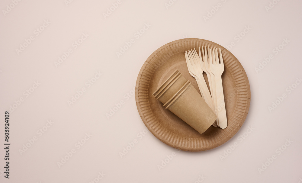 Brown paper cups and plates on a beige background. Recyclable garbage, rejection of plastic