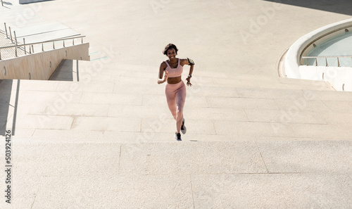 fitness, sport, exercise and lifestyle concept - a young African American woman running upstairs on the city stairs