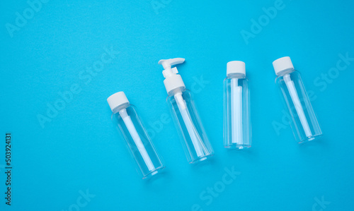 Various transparent empty plastic bottles and jars for cosmetics on a blue background  top view