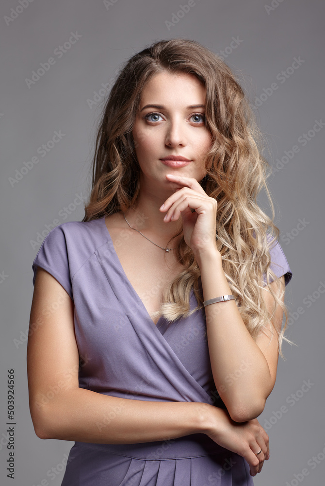 Studio portrait of a young woman in a summer dress. Blond female in a summer dress posing on gray background. Studio portrait of a young woman in a summer dress. Blond female in a summer dress posing on gray background.