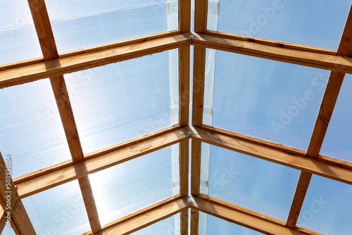 Roof of greenhouse  barn or other agricultural building is made of transparent polycarbonate and wooden boards