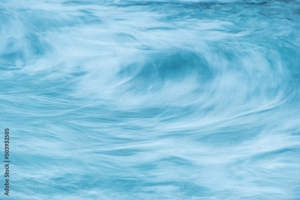 Turquoise ocean waves as backdrop. Sea water boils and foams during surf. Mountain blue river with fast current
