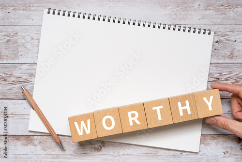 Obraz na plátne 「WORTHY」と書かれた積み木、ノート、ペン、手