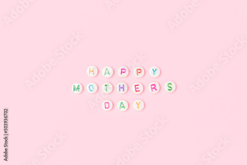 Happy Mothers day. Quote made of white round beads with colorful letters on a pink background. © rorygezfresh