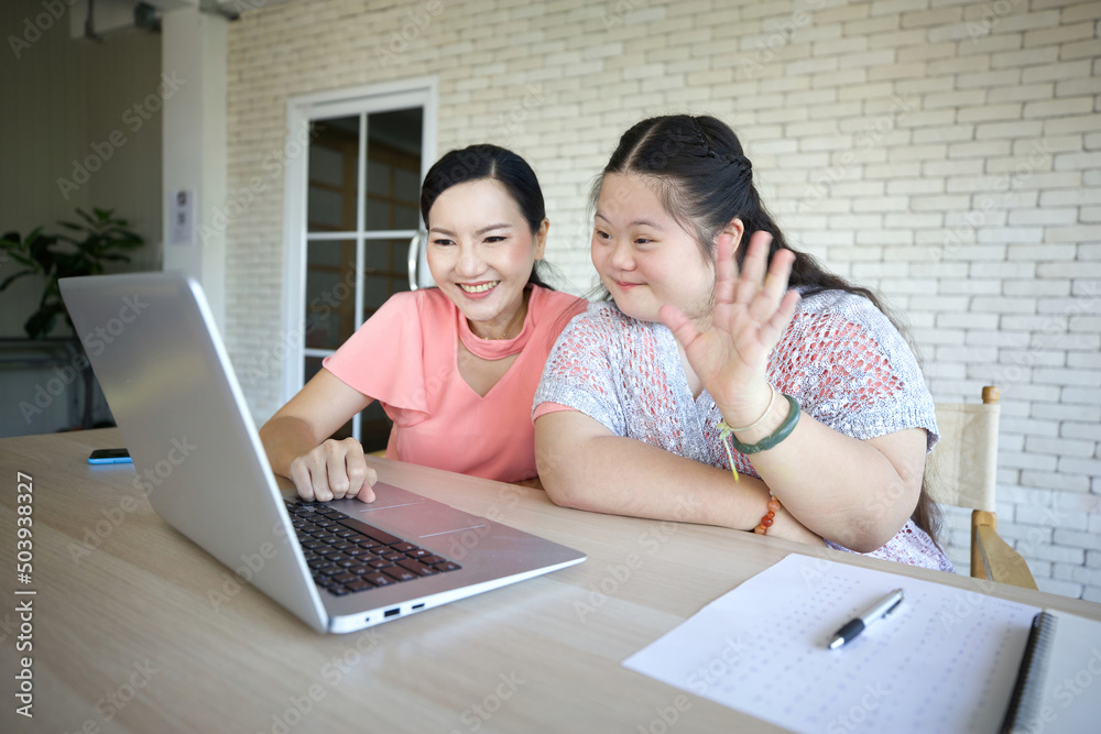 down syndrome teenage girl and her teacher studying how to use laptop computer and talking online to someone down syndrome teenage girl and her teacher studying how to use laptop computer and talking online to someone