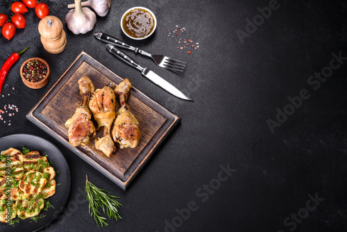 Three chicken legs grilled with spices and herbs on a wooden cutting board