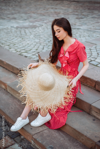 Pretty girl wearing red polka dot dress and white sneakers