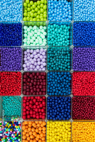 Beads are arranged and sorted by color. Background of colorful bright beads in boxes, set for needlework. High quality photo
