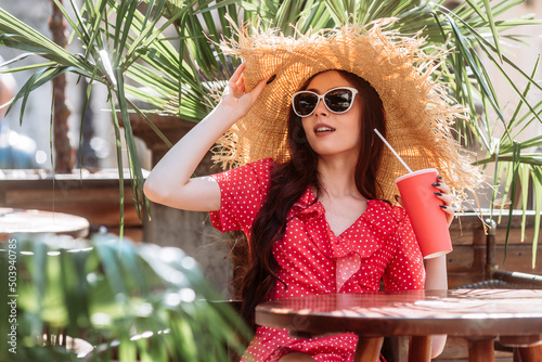 Stylish girl with cold summer drink on the sunny terrace