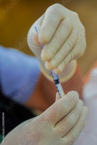 Medical team in full uniform holding syringe taking covid 19 corona virus vaccine from vial bottle preparing for injection Vaccination and immunization against covid-19 Coronavirus immunization.