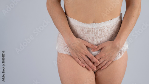 A woman in adult diapers holds her hands on her stomach. Urinary incontinence problem. photo