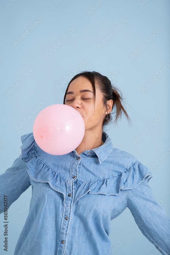 Studio shot of young woman chewing gum and blowing bubble Studio shot of young woman chewing gum and blowing bubble