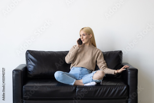 Young woman talk phone listen stay home sit sofa indoors house