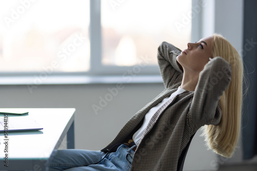 Business young woman relaxing with her hands behind her head and sitting on a chair