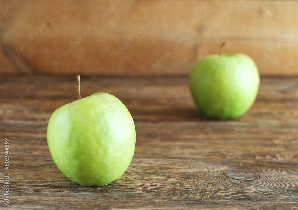 Two green apples lie on a wooden table. Rustic style Two green apples lie on a wooden table. Rustic style