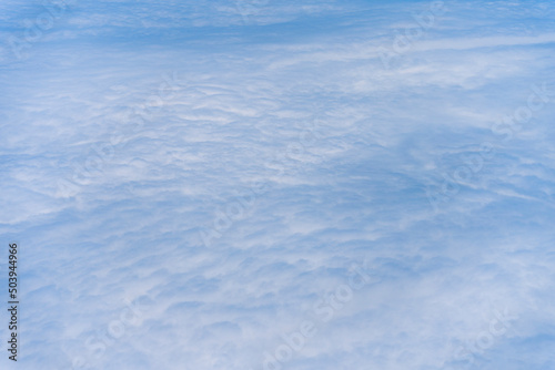 飛行機の窓から眺める空の景色　青空と流れる白い雲
