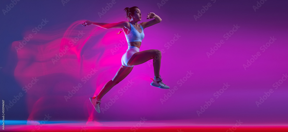 Flyer with professional female athlete, runner training isolated on blue studio background in mixed pink neon light. Sport, motion and action concept.