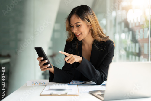 Asian business woman waving fists, got good news on mobile smart phone in office, social media network, video calling, communication. © Natee Meepian