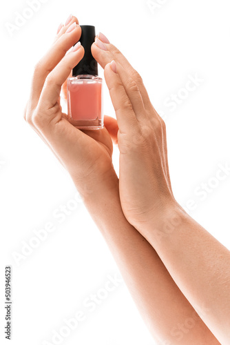 Female hands with beautiful french manicure holding bottle of pink nail polish against white background