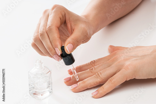 Female hands and bottle of nourishing cuticle oil with a dropper