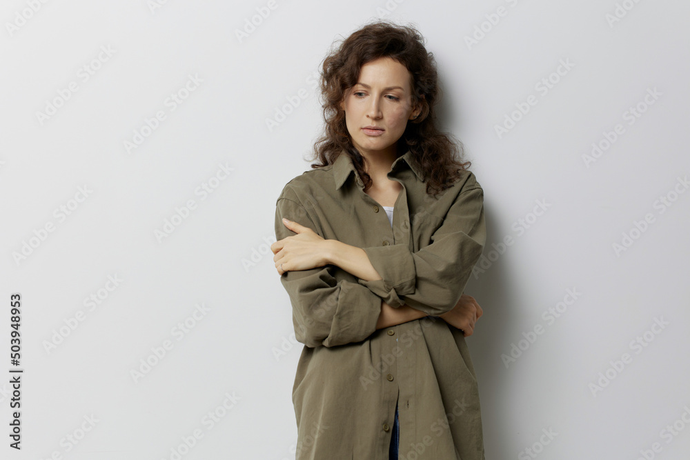 Thoughtful unhappy sad curly beautiful woman in casual khaki green shirt suffering from bad relationship posing isolated on over white background. People Emotions Lifestyle concept. Copy space Thoughtful unhappy sad curly beautiful woman in casual khaki green shirt suffering from bad relationship posing isolated on over white background. People Emotions Lifestyle concept. Copy space