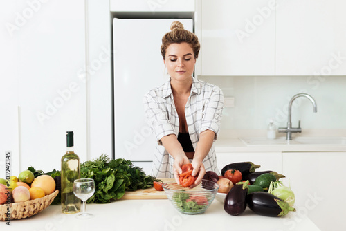 Woman cooking healthy vegetarian dish at home in white kitchen