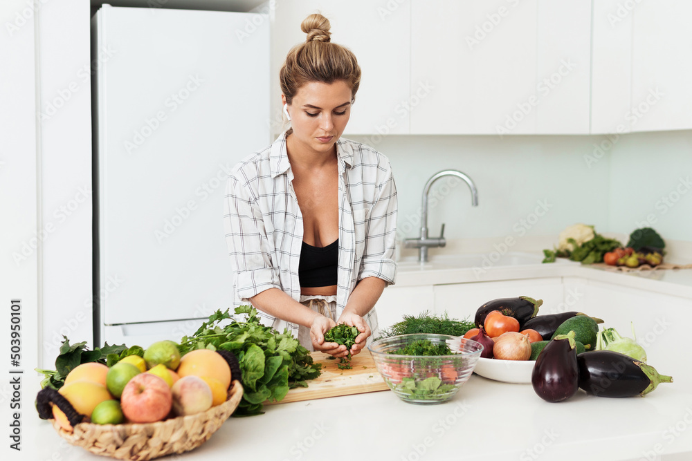 Young pretty woman cooking healthy vegetarian dish at home