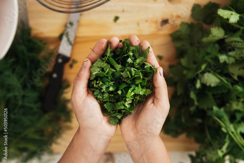 Female hands with handful of chopped coriander leaves