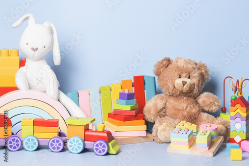 Kid toys collection isolated on blue background. Teddy bear, white bunny, wooden, plastic and fluffy educational baby toy set. Front view © vejaa