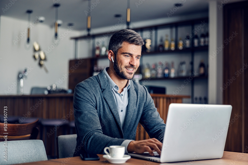 Contemporary businessman using laptop in a coffee shop.