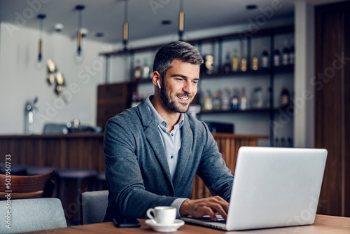 Contemporary businessman using laptop in a coffee shop.