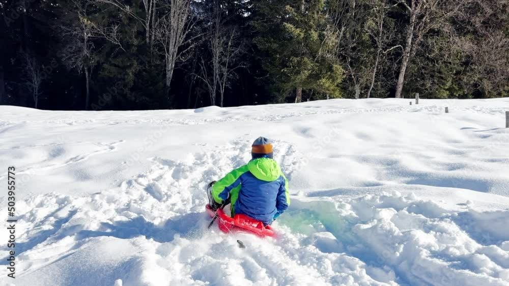 Boy sled downhill having fun in the mountains on winter vacation Boy sled downhill having fun in the mountains on winter vacation