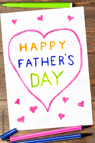 A child's drawing on a wooden table. A postcard for the Father's Day holiday